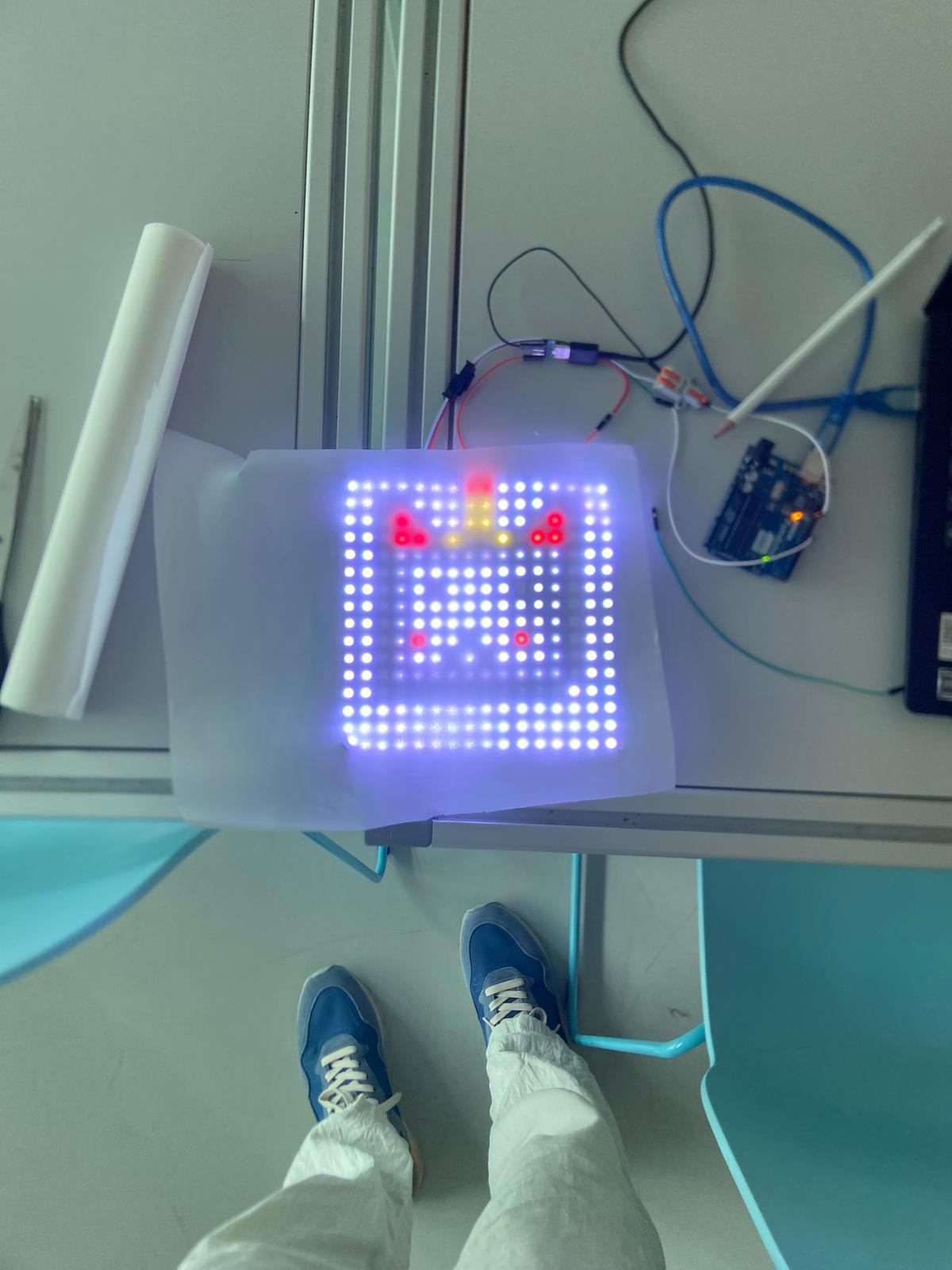 A finished pixel-art face glowing on the RGB LED matrix next to its Arduino